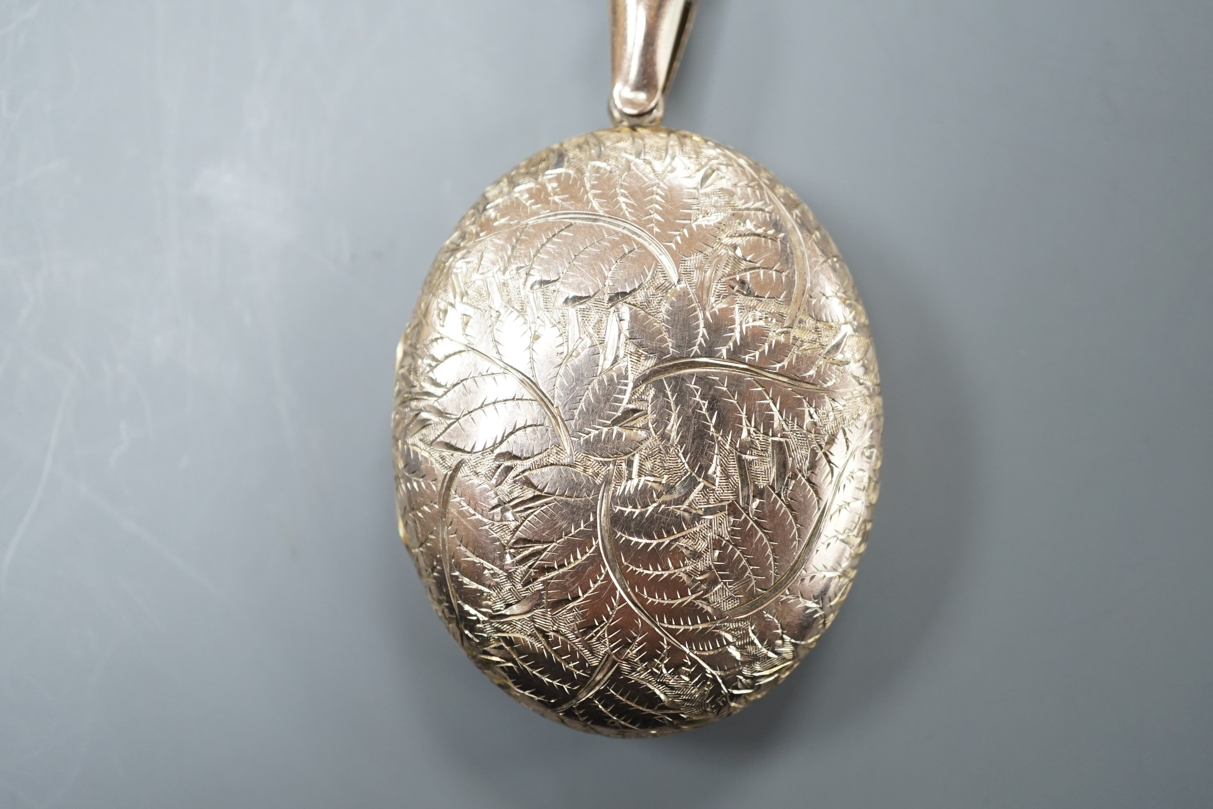 An engraved yellow metal overlaid oval locket, 46mm.